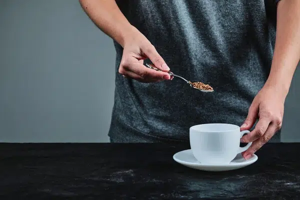 Un homme mesure la dose de café en grain qu'il désire pour sa tasse à café.