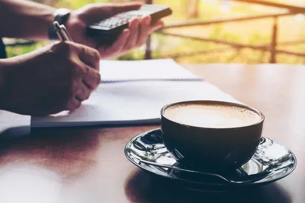 Un comptable calcule le budget café de l'entreprise en buvant une tasse de café.