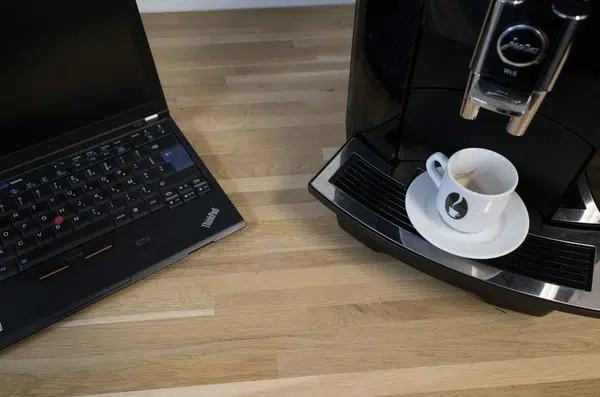 Une machine à café professionnelle de MisterBean, posée juste à côté de l'ordinateur d'un salarié, symbolise l'amélioration de son bien-être grâce à une expertise café maîtrisée.