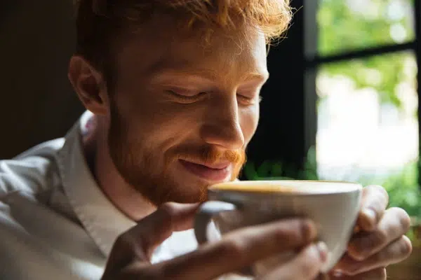 personne buvant un café avec le sourire